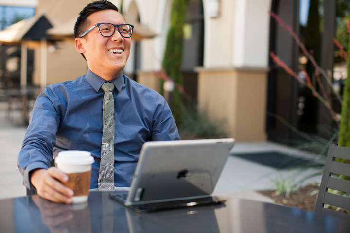 A male CBU student drinking coffee and working on a laptop