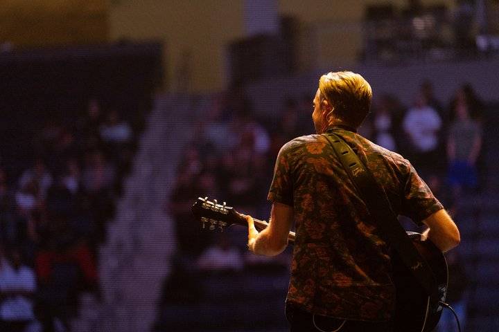 A man playing guitar on stage during a worship service