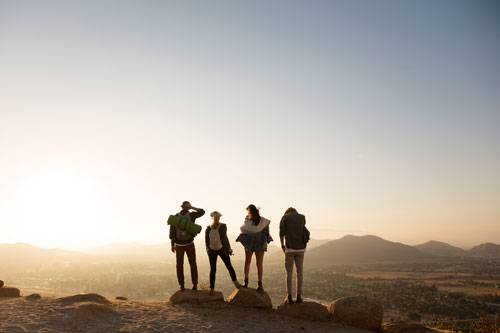 Four students standing at on overlook looking out over a valley with mountains in the distance