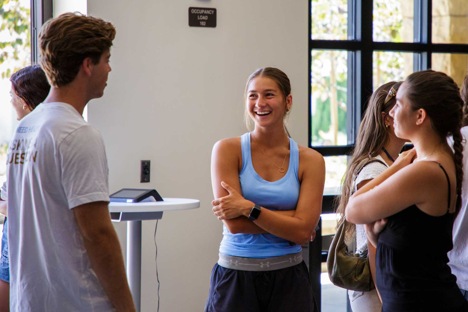 Students talking near windows, sunlight is coming in through windows