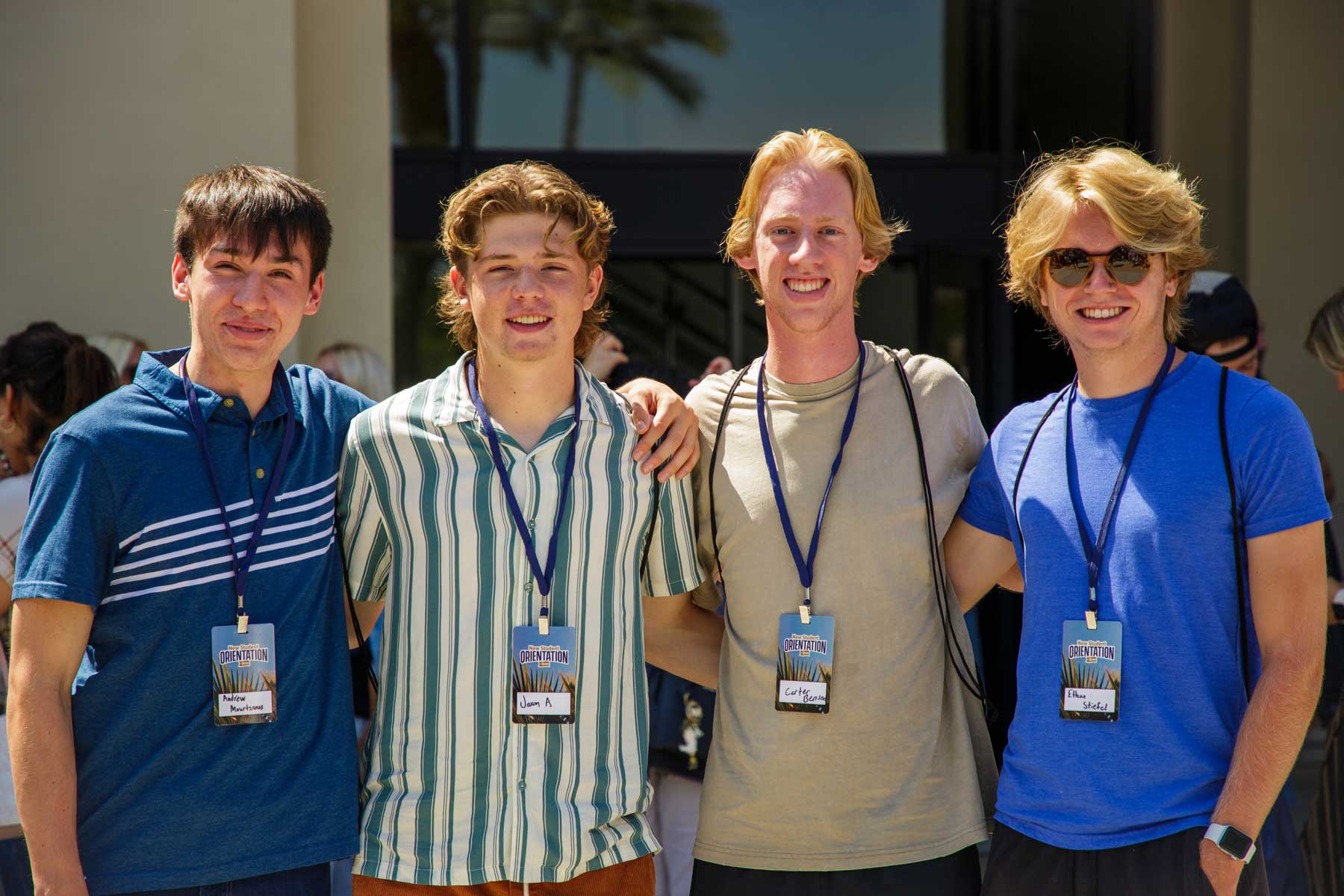 4 students posing with lanyards in front of events center
