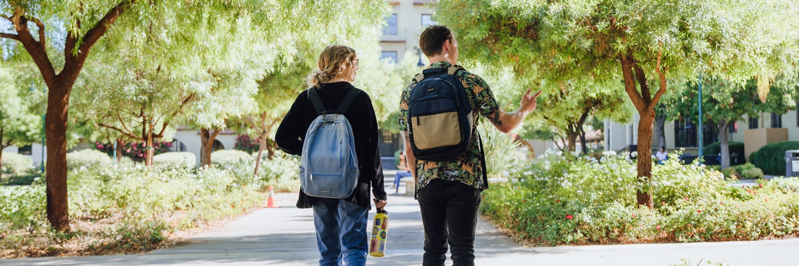 A male and female student with backpacks walk outdoors on California Baptist University's campus